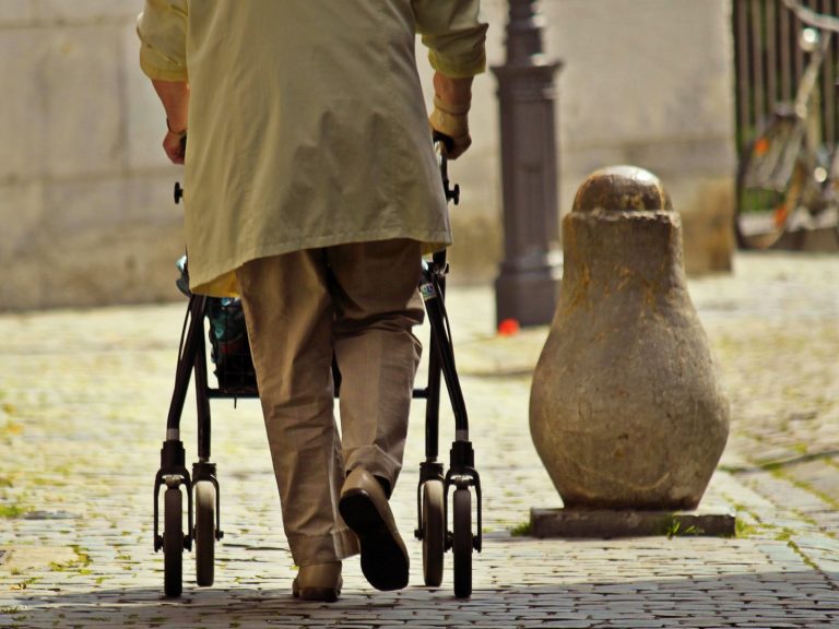 Eine Ältere Person läuft mit einem Rollator durch die Stadt. Eine Reform der Pflegeversicherung ist laut der GKV dringend nötig.