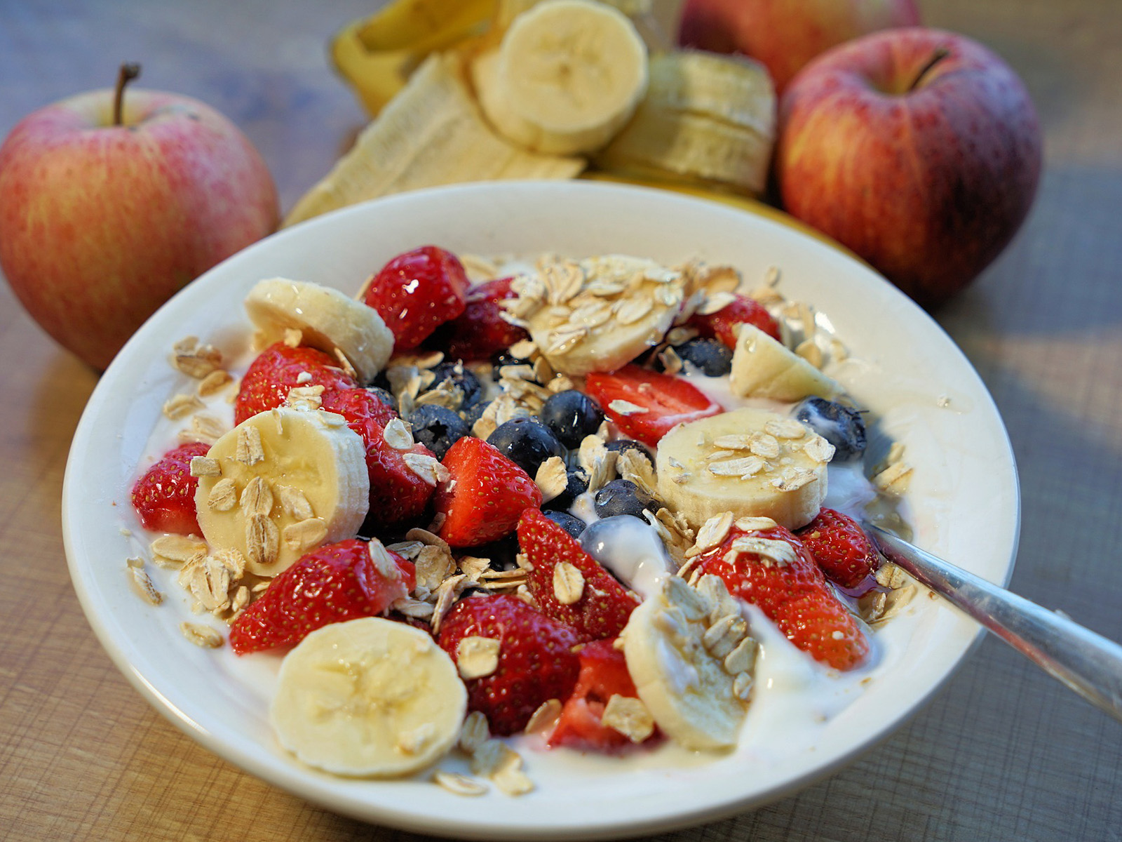 Eine Schüssel mit frischem Beerenobst, Haferflocken, Bananen und Joghurt. Gesunde Ernährung ist im Alter besonders wichtig.