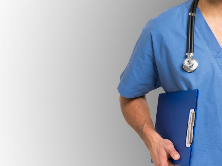 Eine Pflegefachkraft mit einem Stethoskop um den Hals hält ein blaues Klemmbrett in der rechten Hand.