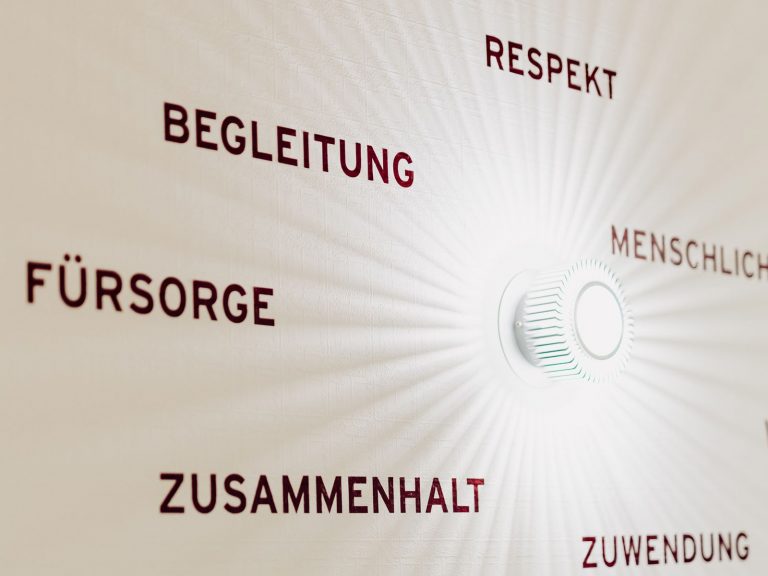 Blick auf eine helle Wand in der solitas-Verwaltung, auf der Begriffe wie Menschlichkeit, Respekt, Begleitung, Zusammenhalt stehen.