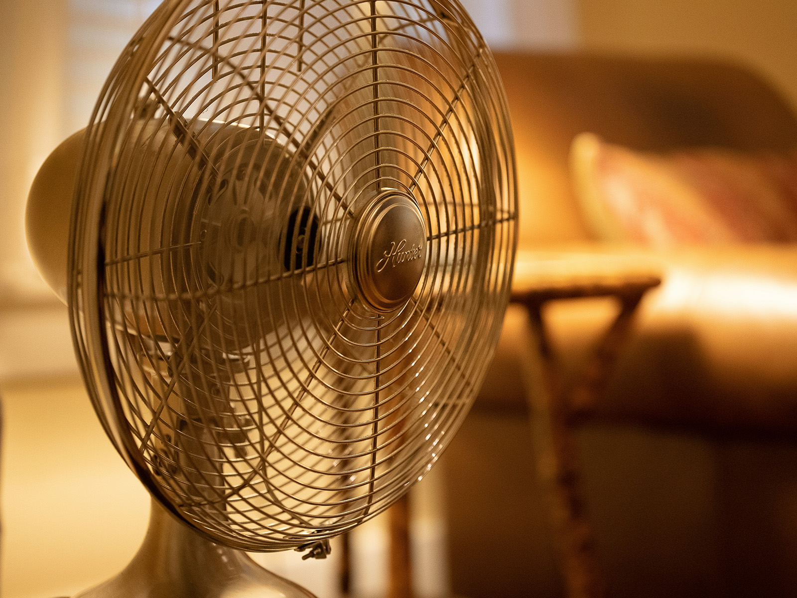 Nahaufnahme eines weißen Standventilators in einem beleuchteten Zimmer. Symbolbild zum Thema "Wohnung abkühlen"