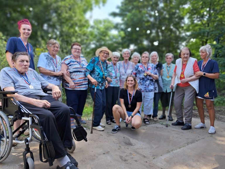 Seniorinnen und Mitarbeiterinnen der Solitas Tagespflege stehen im Halbkreis im Grünen und tragen Medaillen, die sie beim Sommerfest gewonnen haben.