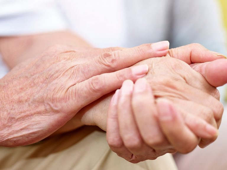Nahaufnahme: Zwei ältere Personen haben ihre Hände ineinander verschränkt. die richtige Hautpflege im Alter hält die Haut gesund und schützt vor Infektionen.