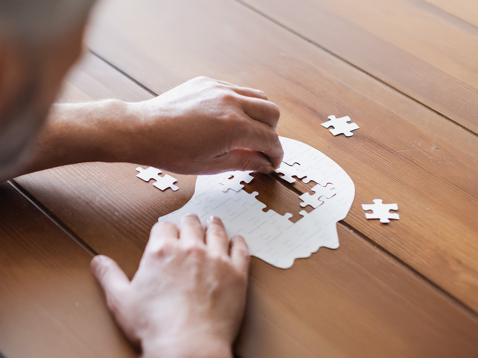 Eine Person legt ein Puzzle in Form eines Kopfes. Durch tägliche Routinen kann man das eigene Demenzrisiko senken.