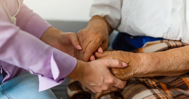 Pflegebedarf erkennen: eine jüngere Person hält die Hände einer älteren Person