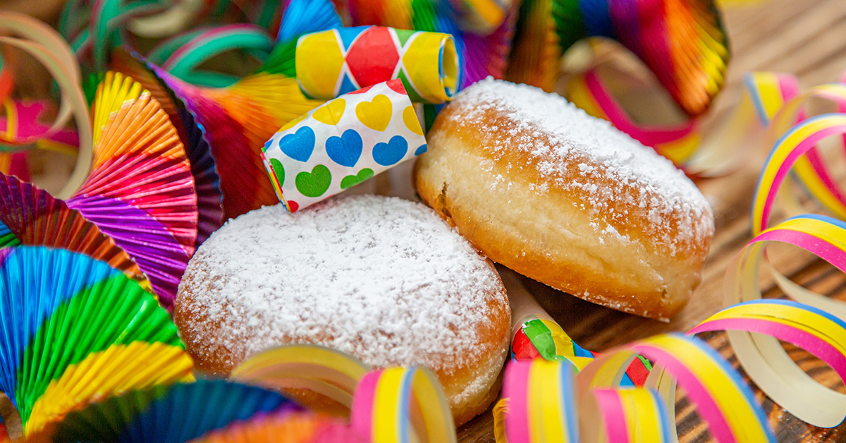 Bunte Luftschlangen und andere Deko für Fasching sowie zwei Pfannkuchen/Berliner.