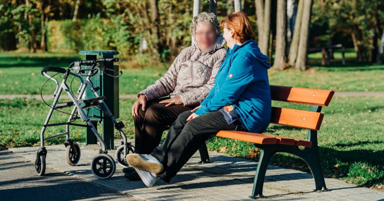 Eine Solitas-Mitarbeiterin und eine ältere Dame sitzen auf einer Bank am Bergwitzsee. 5 neue Sitzbänke dieser Art hat Solitas kürzlich gesponsert.