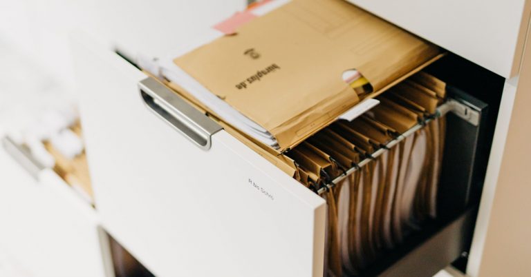 Ein geöffneter Aktenschrank mit vielen gefüllten Hängeordnern.