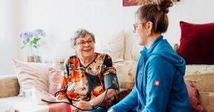 Eine Mitarbeiterin von Solitas misst bei einer Klientin Blutdruck. Diese Hausbesuche sind typisch für den Pflege-Beruf.