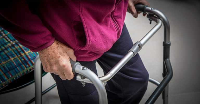 Eine ältere Person schiebt einen Rollator.