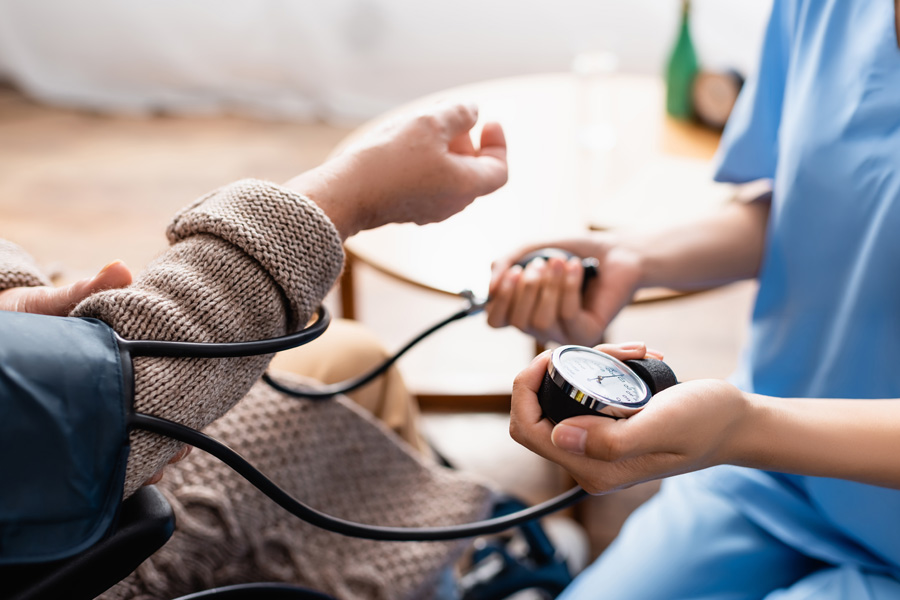 Eine Pflegefachfrau misst den Blutdruck bei einem älteren Patienten